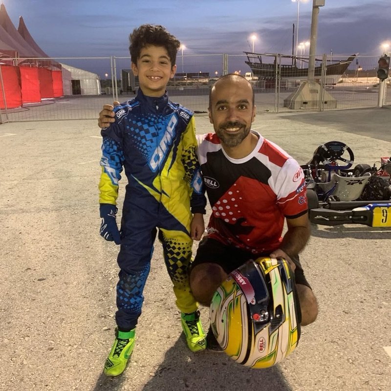 Young Khalid in his first race suit beside his coach, who holds his helmet