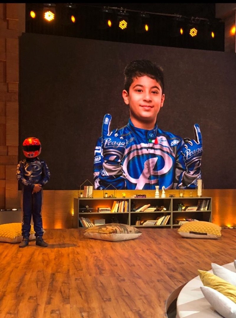 Khalid in his Praga suit on the set of MBC's Little Stars, his photo on the studio screen behind him